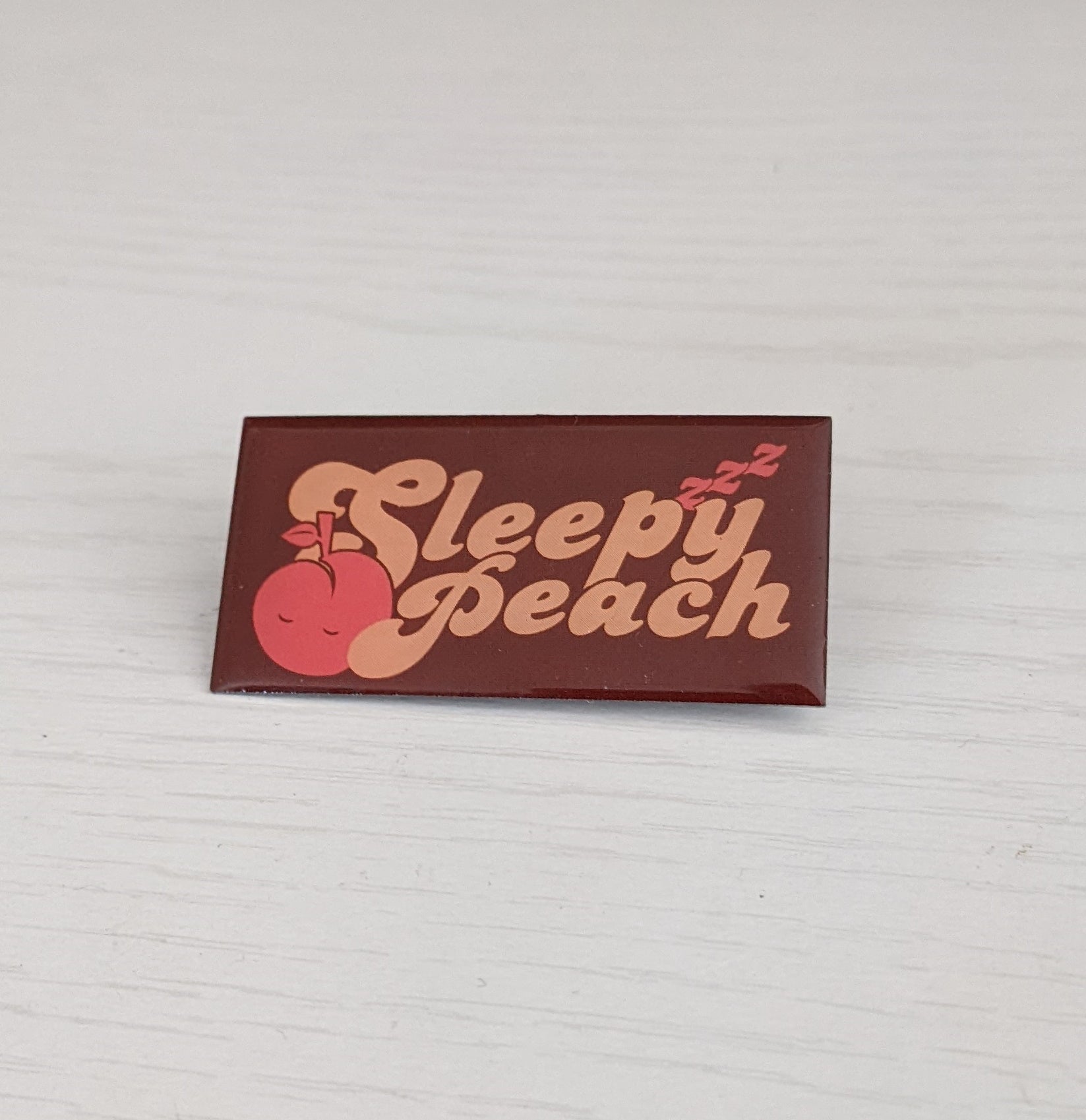 Sleepy Peach logo enamel pin.